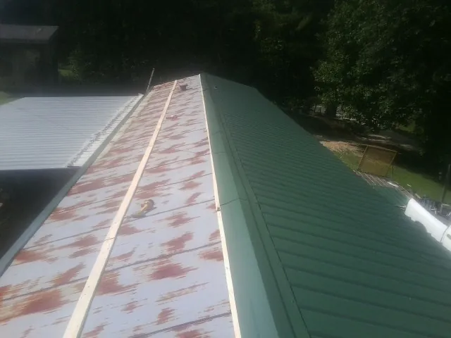Old rusted panels beside newly installed green metal roofing — Wind Damage Roof Repair by Roofing Brothers in Cary