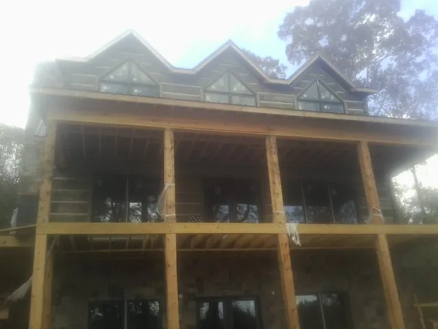Dormers and porch framing on a large log home under construction — Roof Coating work by our crew in Cary