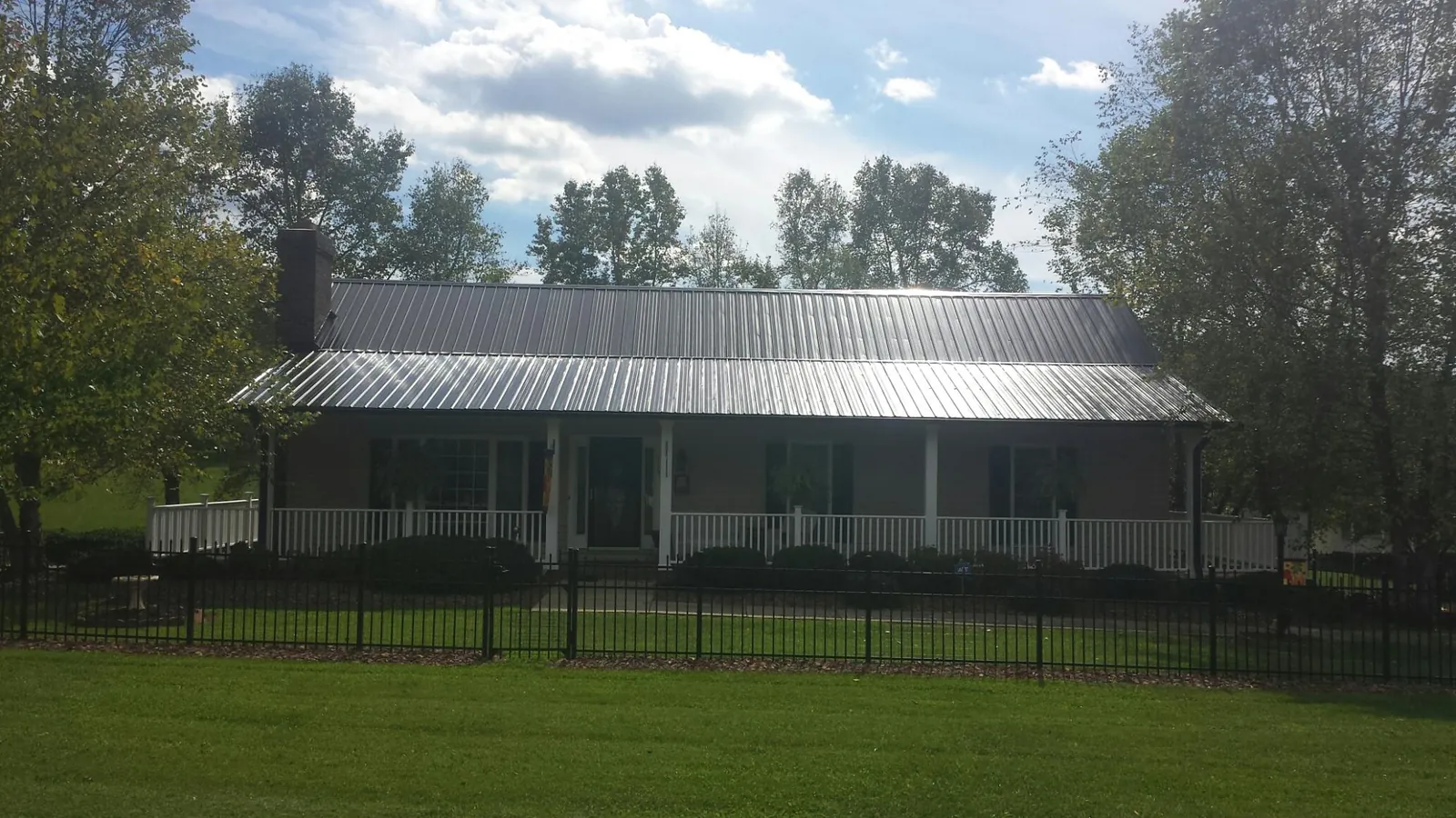 Gray metal roof on a brick ranch with a full width front porch — Gutter Guard Installation work by our crew in Cary