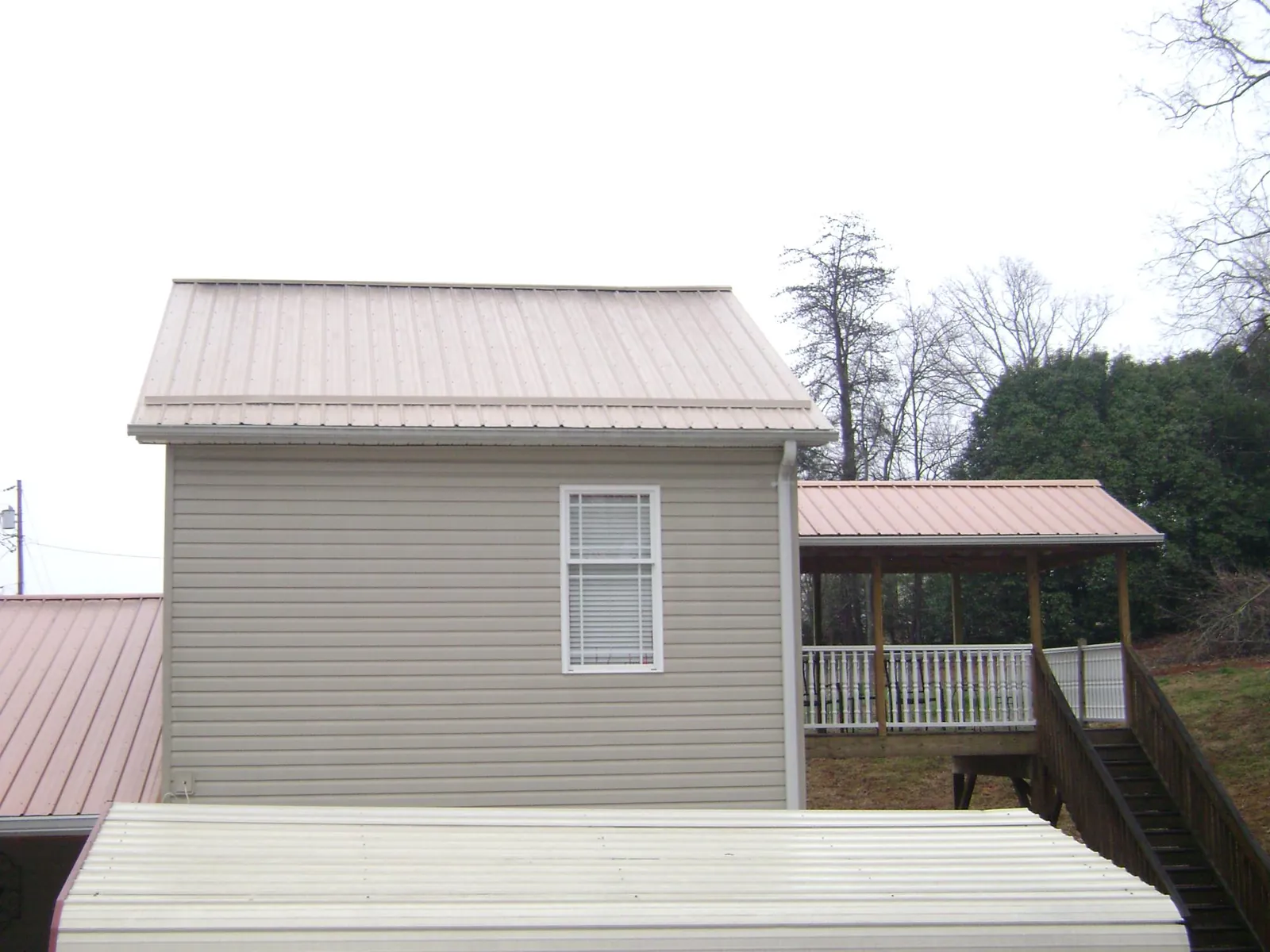 Tan metal roofs on a two story addition and attached porch, from a Roof Replacement job in Cary